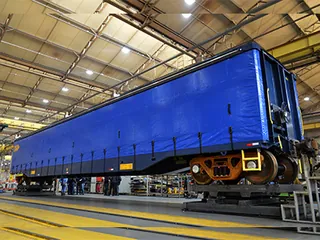 Vagão ferroviário com cortina sider azul dentro de um galpão